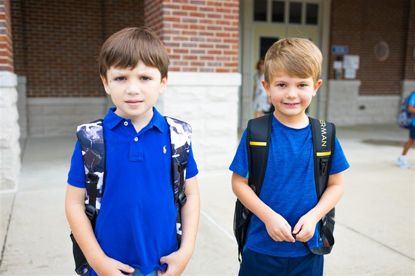 Two boys wearing blue shirts smile